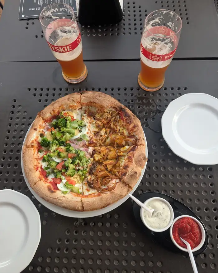 Pizza pół na pół i dwa piwa na stoliku na tarasie